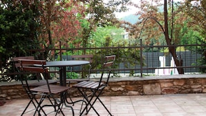 An outdoor patio with a round table and four chairs, surrounded by a stone wall and a metal fence. - Large outdoor terrace - Ground floor flat in a lovely Italian village (Dumenza)