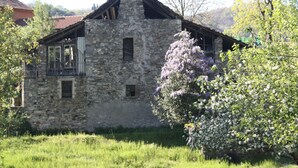 A stone building with a sloped roof, multiple windows, and a balcony. - Large outdoor terrace - Ground floor flat in a lovely Italian village (Dumenza)