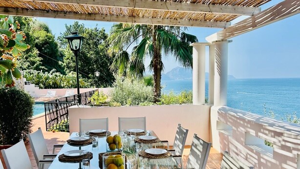A dining table set for six with a view of the sea and mountains. - Beautiful panoramic villa in a private park with descent to the sea (Massa Lubrense)