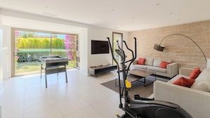 Un salon moderne équipé d’un tapis de course, d’un canapé, d’une table basse et d’un téléviseur.