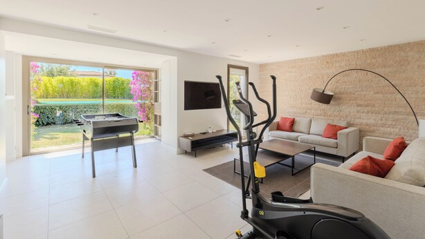 Ein modernes Wohnzimmer mit Laufband, Sofa, Couchtisch und Fernseher.