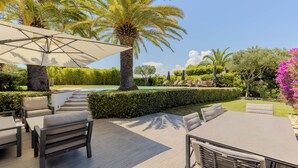 Eine Außenpatio mit Pool, Liegestühlen und Sonnenschirmen.