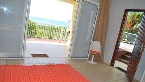 Un dormitorio con cama, un balcón con vistas al mar y una puerta que da a una escalera.