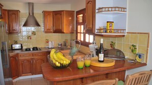 Una cocina con armarios de madera, una isla central con frutero, un tostador y una botella de vino.