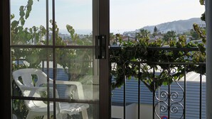 Une vue à travers une fenêtre, avec une grille en métal et une chaise en plastique blanche.