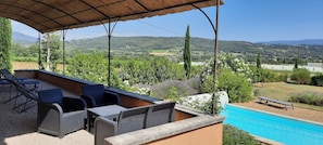Eine Terrasse im Freien mit Korbmöbeln und einem Pool.