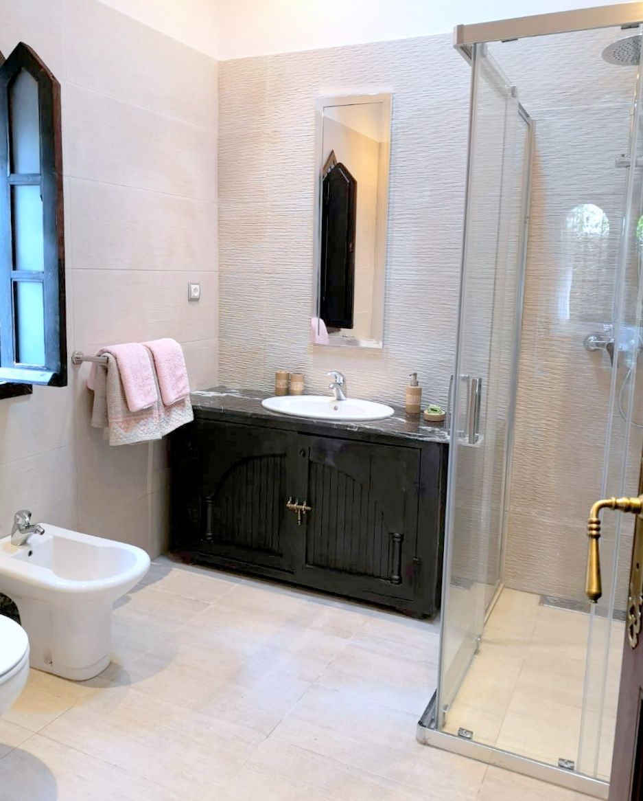 A bathroom with a bidet, a sink with a mirror, and a glass-enclosed shower.