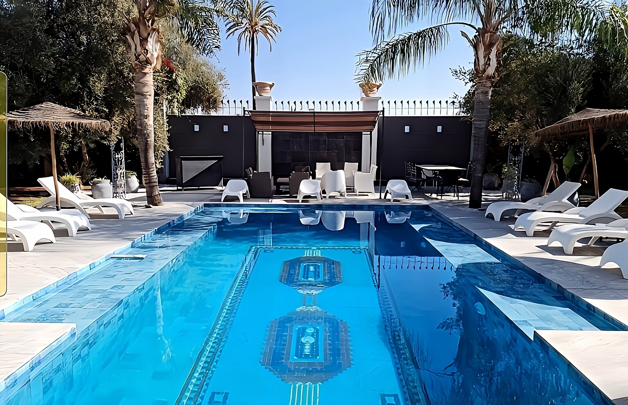 Una piscina con tumbonas y palmeras.