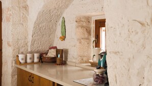 Una cocina con paredes de piedra, armarios de madera y diversos utensilios.