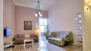 Una sala de estar con un sofá, una mesa de centro, un televisor y una estantería.