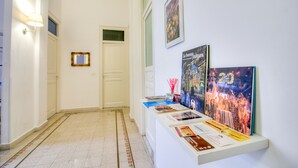 Un pasillo con suelo de baldosas, una puerta blanca y una pared decorada con cuadros y carteles informativos.