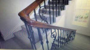 Eine Treppe mit hölzernem Geländer und schwarzen Metallspindeln.