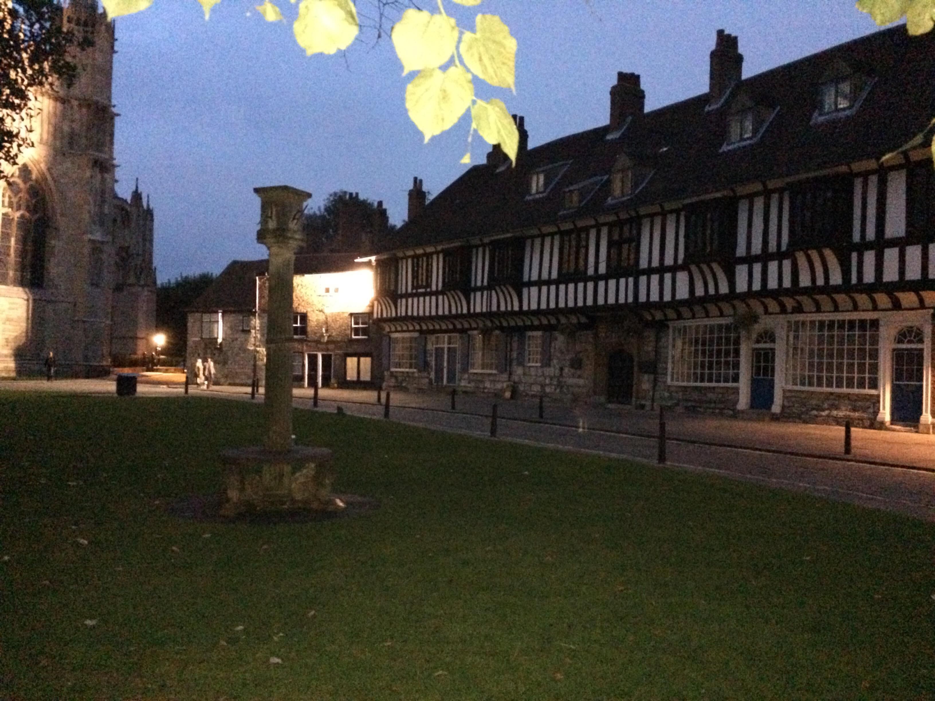 A historic building with a traditional half-timbered facade, a stone tower, and a well-maintained lawn.