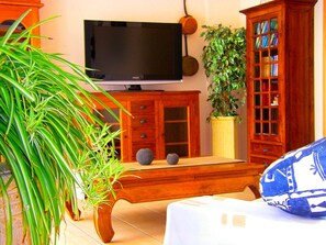 A living room with a television, wooden cabinets, a plant, and a sofa.