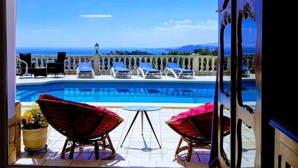Un área de piscina con sillones de descanso y vista al mar.