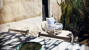 Zona d'estar a l'aire lliure amb sol, una cadira blanca i un bol.