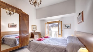 Een hotelkamer met twee bedden, een grote spiegel, een kroonluchter en uitzicht op buiten.