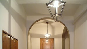 Een gang met een houten deur, een marmeren vloer en een hangende lamp.