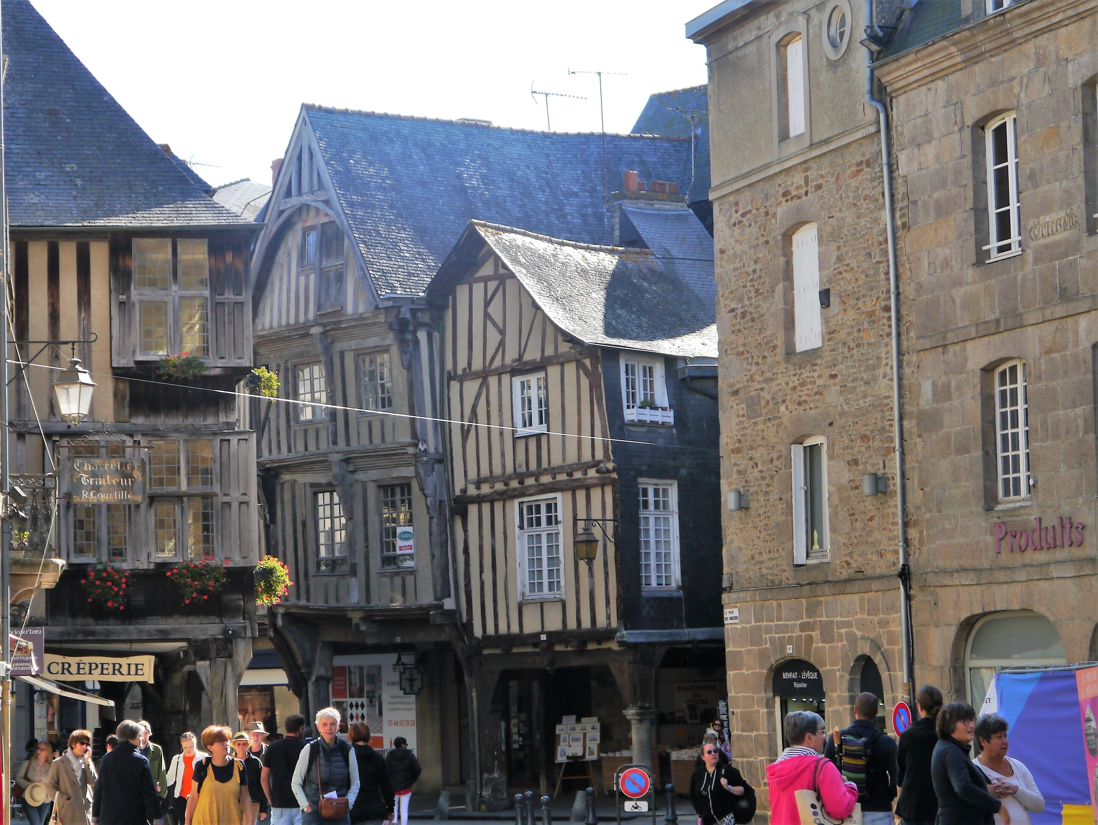 A narrow street with traditional half-timbered buildings, a sign for 'Crêperie', and a 'Products' sign on a stone building.