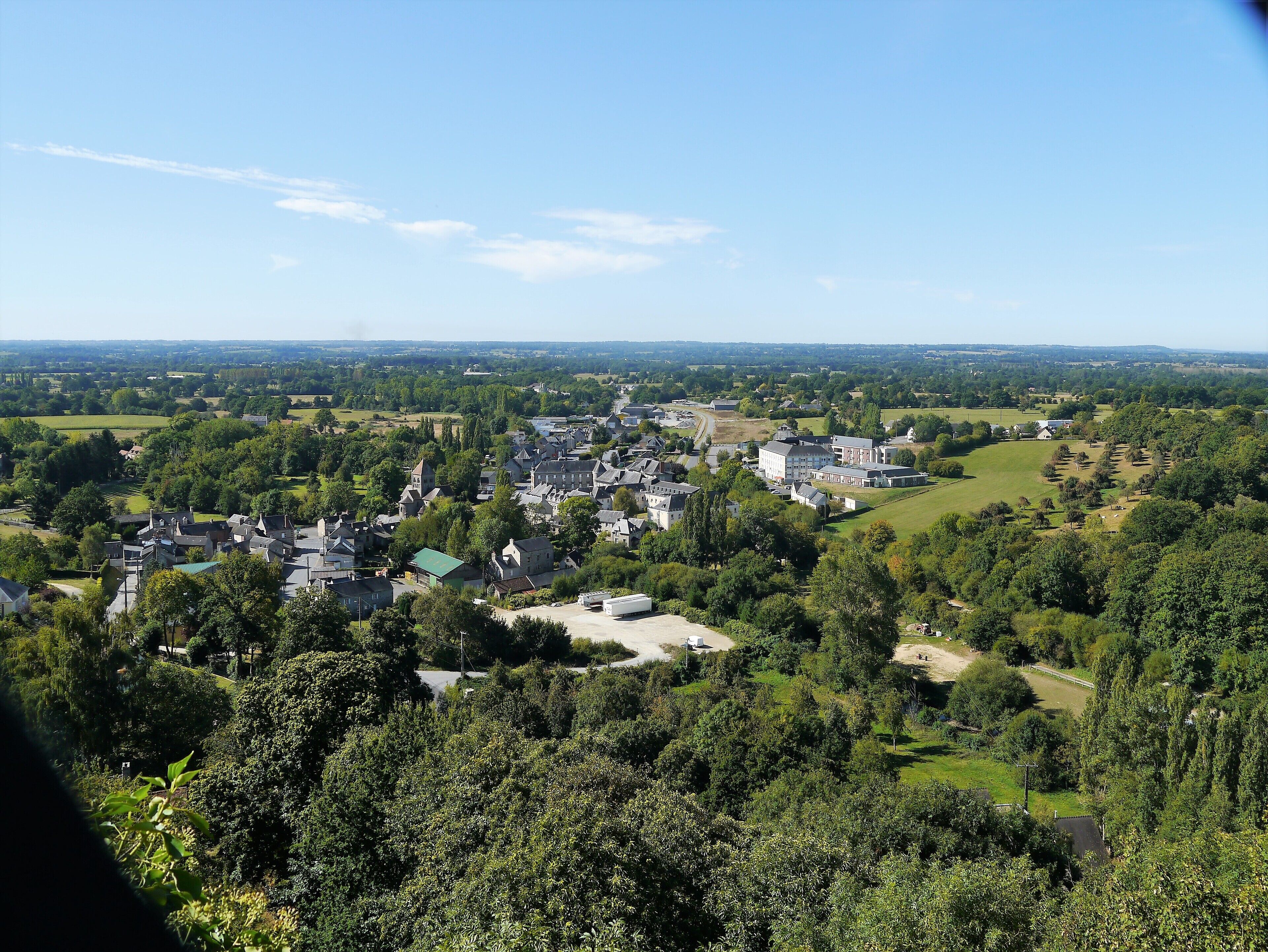 A town with a mix of residential and commercial buildings, surrounded by greenery and open fields.
