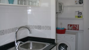 Uma cozinha compacta com pia, máquina de lavar e micro-ondas.