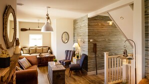 Un salon chaleureux avec un mur en bois, un escalier et une vue sur l’extérieur.