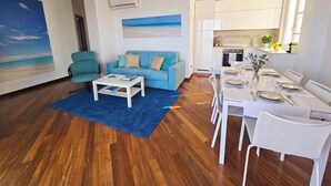 Una sala de estar moderna con un sofá azul, una mesa de centro y un cuadro de una playa.