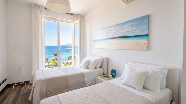 Habitación de hotel con dos camas, un ventanal con vistas al mar y un cuadro en la pared.