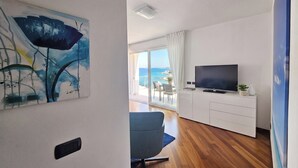 Una sala de estar moderna con un televisor de pantalla plana, un sillón azul y un cuadro en la pared.