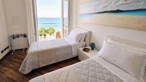 Habitación de hotel con dos camas, un cuadro de playa y vista al mar.