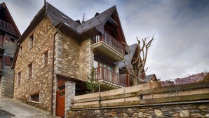 Un bâtiment en pierre doté d’un balcon en bois, d’une porte en bois et d’un mur en pierre.
