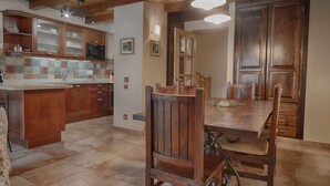 Une cuisine avec des meubles en bois, un pare-feu en carrelage et un coin repas comprenant une table et des chaises en bois.