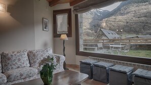 Un salon confortable avec un canapé, une table et une vue sur un paysage montagneux par la fenêtre.