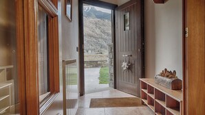 Une porte en bois qui donne sur un sentier de pierres, avec une vue sur un paysage montagneux.