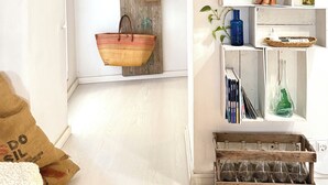 A compact room with a rustic aesthetic, featuring a wooden wall-mounted shelf with a woven basket, a small wooden sculpture, and a black object labeled 'IOMT'. - Unique and charming apartment, in the historic center. Incomparable! (Santanyí)