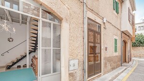 A building with a stone facade, a staircase leading to a balcony, and a door with a glass panel. - Unique and charming apartment, in the historic center. Incomparable! (Santanyí)