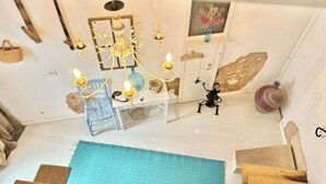 A room with a chandelier, wooden furniture, a blue rug, and a stone wall. - Unique and charming apartment, in the historic center. Incomparable! (Santanyí)