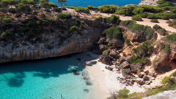 A coastal landscape with clear turquoise waters, rocky terrain, and sparse vegetation. - Unique and charming apartment, in the historic center. Incomparable! (Santanyí)