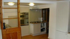 Una cocina compacta con horno empotrado, estufa a gas y microondas.