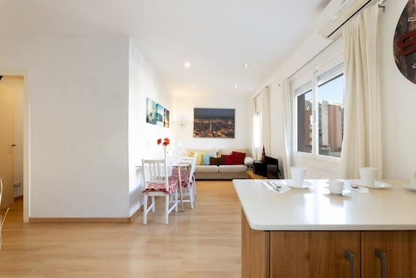 A modern living room with a sofa, a dining table with chairs, and a kitchen area with a counter.