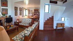 A spacious living room with a sofa, a coffee table, and a television. There is a staircase leading to another level.