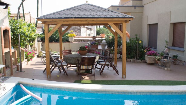 A pool area with a wooden gazebo, outdoor seating, and potted plants. - Spacious and bright apartment on the Costa Brava, landscape of the painter S. Dalí (Castelló d'Empúries)