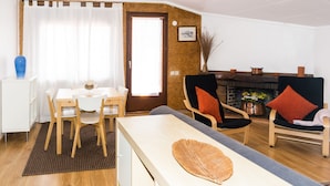 A modern living room with a dining area, wooden furniture, and a fireplace. - Spacious and bright apartment on the Costa Brava, landscape of the painter S. Dalí (Castelló d'Empúries)