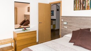 A bedroom with a bed, wooden dresser, and a mirror. - Spacious and bright apartment on the Costa Brava, landscape of the painter S. Dalí (Castelló d'Empúries)