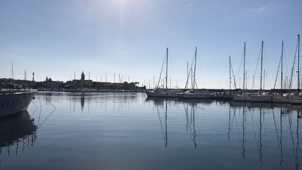 A marina with multiple sailboats docked, calm water, and a clear sky. - Gemma - apartment holiday home (Desenzano del Garda)