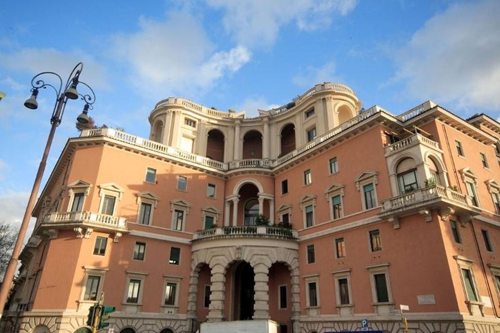 Um edifício grande e histórico com um pátio central, várias varandas e detalhes arquitetônicos clássicos.
