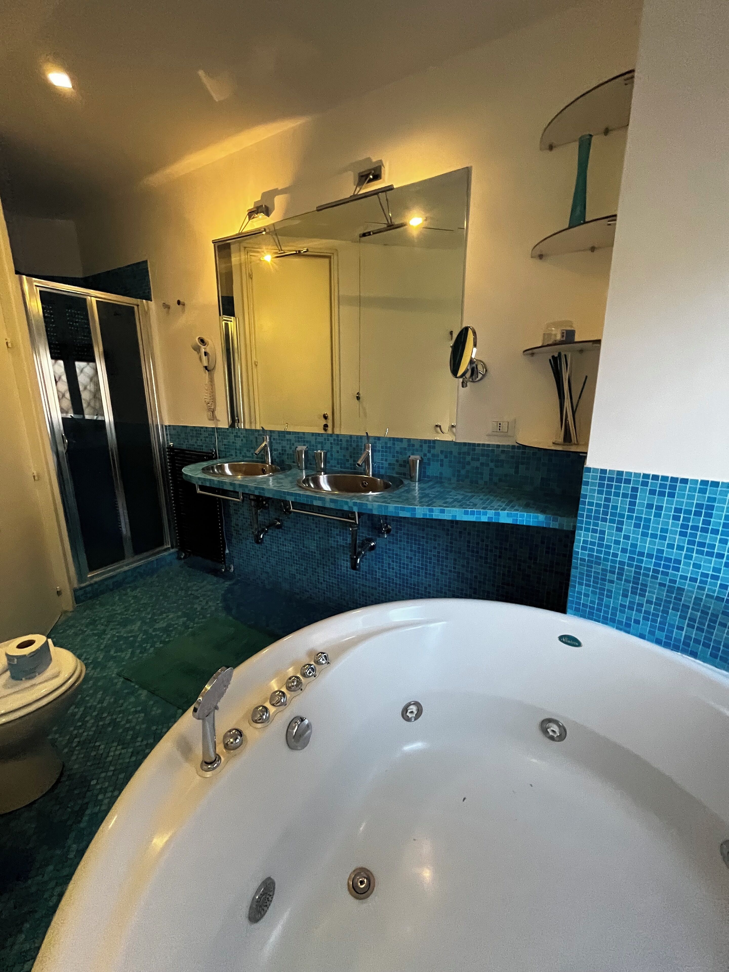 A bathroom with a large bathtub, two sinks, a mirror, and a shower area.