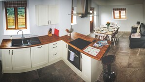 A kitchen with a wooden countertop, white cabinets, a built-in oven, and a dining area with a table and chairs. - High Peak converted barn with private garden and stunning views  (HIGH PEAK)