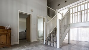 A spacious room with a staircase leading to an upper level, a wooden cabinet, and a door leading to another room. - High Peak converted barn with private garden and stunning views  (HIGH PEAK)