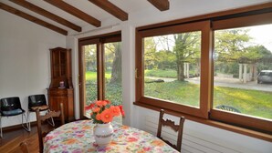 A room with a wooden ceiling, a large window with a view of a garden, a wooden cabinet, and a table with a floral tablecloth and a vase with flowers. - Padua Villa with large private park (Campodarsego)